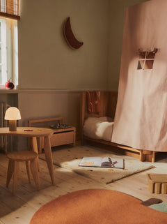 Skye Parchment rug laid beside a wooden bed with a picture book on top
