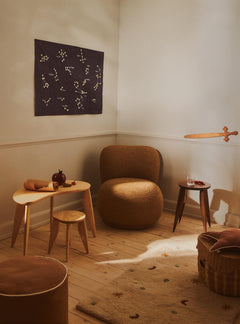 Corner of the Skye Parchment rug in a sunlit room with a bouclé chair