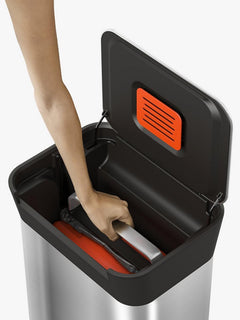 Hand reaching into the open Titan 30L bin to release the compaction plate