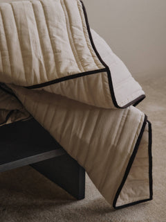 Close view of the Vari bedspread's channel quilting and dark chocolate piping