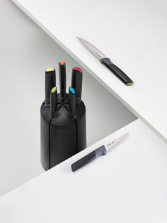 Elevate knives with multicolour handles resting beside the carousel block