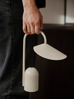 Arum Portable Lamp in Cashmere carried by its arched handle