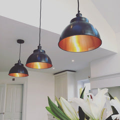 Pewter and copper dome pendant lights hanging above a kitchen worktop