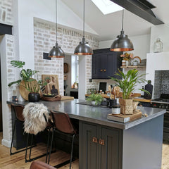 Pewter and copper dome pendants lit above a kitchen dining area