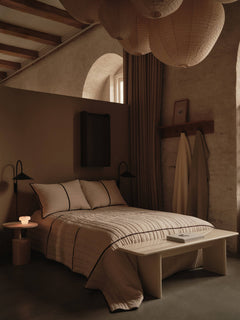 Vari quilted bedspread in Natural/Dark Chocolate laid over a bed in a warm-toned bedroom