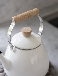 Close-up of the beech handle and matching lid knob on the white enamel stove kettle