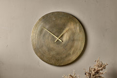 Okota antique brass wall clock hung on a neutral plaster wall