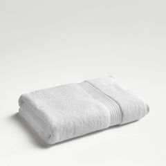 Christy Supreme Hygro bath sheet in white, folded on a plain pale background