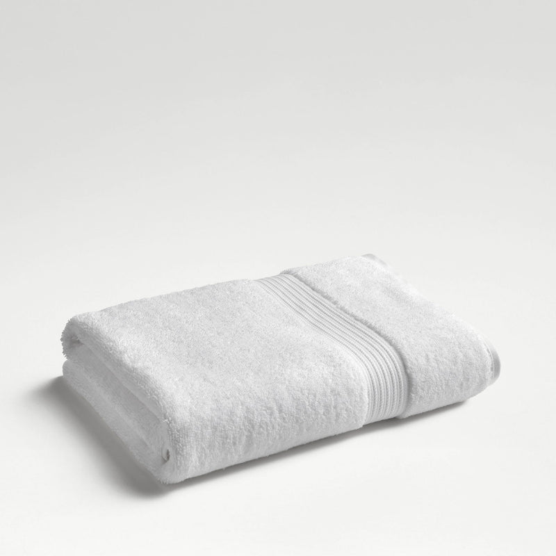 Christy Supreme Hygro bath sheet in white, folded on a plain pale background