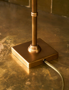 Close-up of the square antique brass base and reeded column of the Kelmscot table lamp