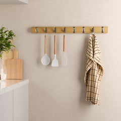 Umbra Flip 8 natural wood rail in a kitchen with utensils and a tea towel hanging from the nickel hooks