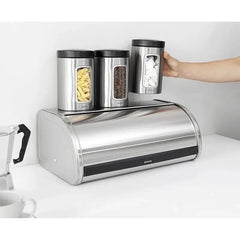 Storage canisters standing on the flat top of the matt steel Roll Top bread bin