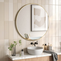 Umbra Hubba brass round mirror above a basin in a tiled bathroom