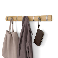 Natural and nickel Umbra Flip 8 rail on a pale wall holding a bag, coat and small purse