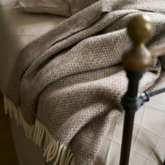 Sand Lima throw draped over the end of an iron bed