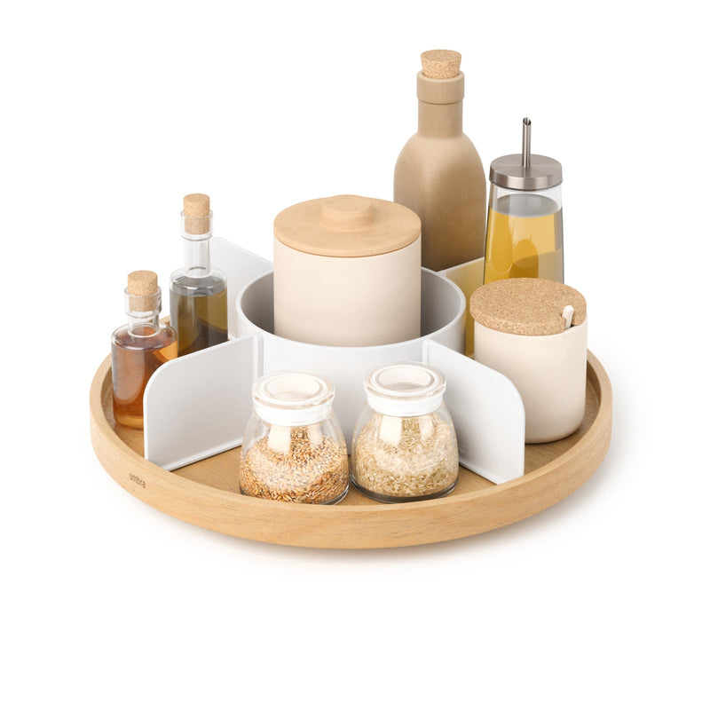 Umbra Bellwood lazy Susan in white and natural wood, filled with oils and spice jars, on a white background