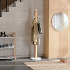 Umbra Flapper coat rack in white and natural standing in a hallway beside a shoe rack and round mirror