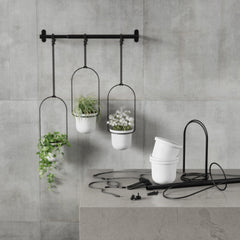Triflora hanging planter set shown on a concrete wall with its pot and fixings laid out below
